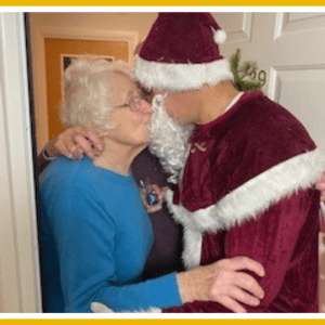 Resident wearing blue jumper hugs man dressed in Santa outfit