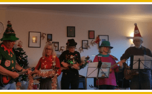 Five people wearing Christmas outfits play a ukulele in room
